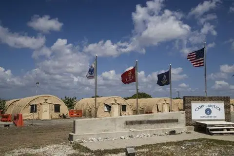In this photo reviewed by US military officials, flags fly in front of the tents of Camp Justice, April 18, 2019, in Guantanamo Bay Naval Base, Cuba. © 2019 AP Photo/Alex Brandon